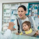 mother with a child testing hand cream in pharmacy